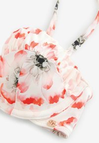 Top de bikini floral en tela suave y elástica con flores rosas y coral, bordes fruncidos y tirantes delgados ajustables con herrajes metálicos.