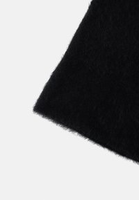 Czarna, puszysta tkanina o miękkiej fakturze. Krawędź lekko postrzępiona, co podkreśla przytulny, subtelny design. Idealna do zapewnienia ciepła.