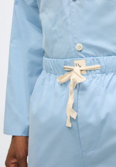 Svetlo modra jakna z gumbnim zapiranjem, elastičnim pasom in kremasto belim vrvico z etiketo. Gladek, lahkoten material.