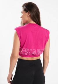 Roze cropped t-shirt met een ronde halslijn en elastische zoom, met witte tekst "Gorilla Wear" in vetgedrukte letters op de achterkant.