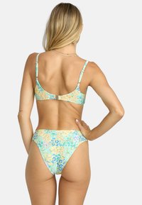 Bloemige bikini in pastelgeel, blauw en groen. Beschikt over een bandontwerp met verstelbare hardware en een geribbelde textuur op de stof.