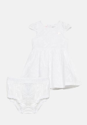 Biele detské šaty s krátkymi rukávmi a zodpovedajúcimi nohavičkami, s jemnou kvetinovou výšivkou a malým dekoratívnym logom na hrudi.