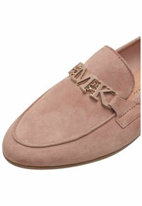 Pink suede loafers featuring a gold-tone "MK" logo accent and stitched detailing along the upper edge. Smooth texture with a rounded toe.