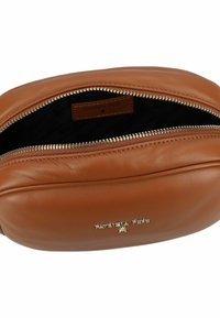 Borsa a tracolla in pelle color tan con chiusura a zip. Presenta un'etichetta logo all'interno e una superficie liscia con una forma curva. Dettaglio della zip in metallo.