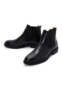 Botas Chelsea de cuero negro con paneles laterales elásticos, textura suave, punta redonda, suela plana de goma y lengüetas traseras para ponerlas con facilidad.