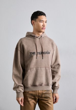 Brauner Baumwollhoodie mit einer Vordertasche, verstellbarem Kapuzenzug und grafischem Textdesign. Lockerer Schnitt mit gerippten Bündchen und Saum.