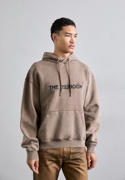 Haut en coton brun avec une poche avant, une capuche avec cordon de serrage et un design graphique au texte. Coupe décontractée avec des poignets et un ourlet côtelés.