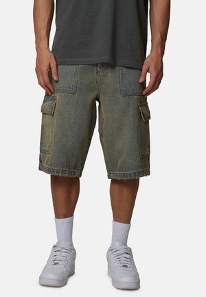 Denim cargoshorts in lichtblauw met een vervaagde afwerking, voorzien van zijzakken, zichtbare stiksels en een ontspannen pasvorm, gedragen met witte sneakers.