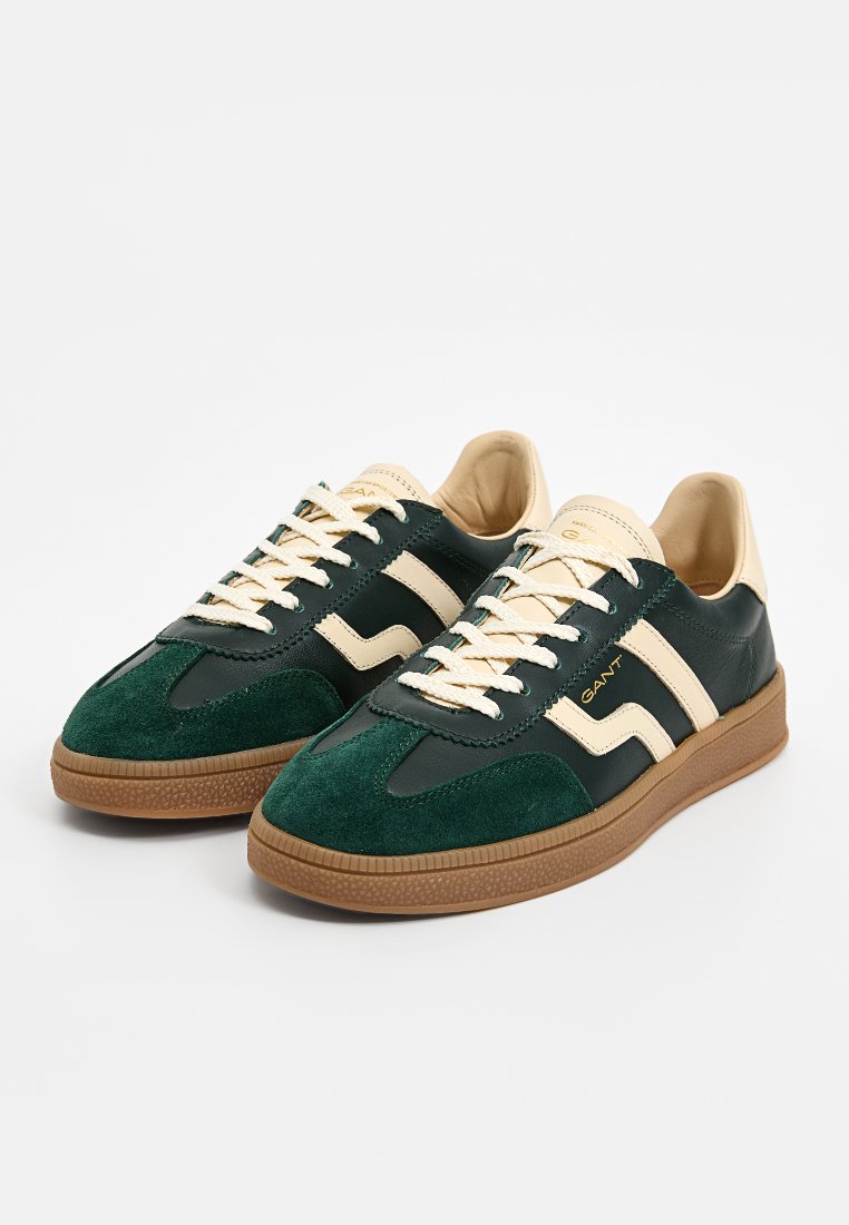 Zielone i granatowe skórzane sneakersy z kremowymi akcentami, teksturowana zamszowa cholewka, płaskie sznurowadła oraz gumowa podeszwa. Posiadają dwa boczne paski.