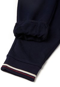 Námořnické modré tepláky s žebrovaným manžetou, zdobené červenými, bílými a modrými pruhovanými detaily na lemu a měkkou, strukturovanou tkaninou.