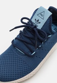 Námořnické modré pletené sportovní boty s texturovaným svrškem, světle modrými akcenty, kontrastní bílou podrážkou a výrazným systémem šněrování.