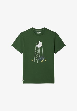 T-shirt en coton vert présentant un graphique d'un fauteuil d'arbitre de tennis blanc avec des balles de tennis à la base. Col rond et manches courtes.