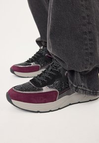 Scarpe da ginnastica nere e borgogna con una tomaia glitterata testurizzata, dettagli in camoscio e una robusta suola grigia. Design con lacci e punta rinforzata.