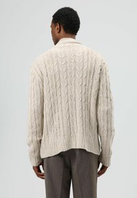 Vest met kabelpatroon in lichtbeige, met een geribbelde zoom en een ontspannen pasvorm. Het gestructureerde patroon zorgt voor visuele aantrekkingskracht.