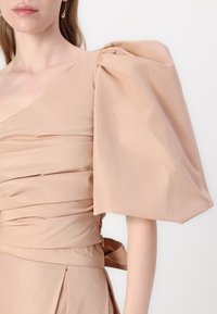 Dusky pink dress featuring a one-shoulder design, ruched bodice, and voluminous puff sleeve with smooth, textured fabric.