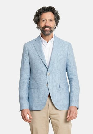 Blazer de lino azul claro con un diseño texturizado, solapas de muesca, dos botones y dos bolsillos frontales, combinado con una camisa blanca y pantalones beiges.