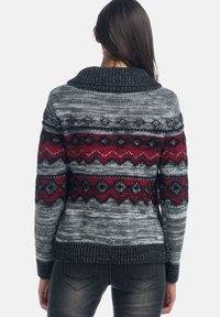 Pletený svetr s texturovaným šedým základem, červenými a černými vzorovanými akcenty a širokým límcem. Design doplňují žebrované manžety a spodní lem.