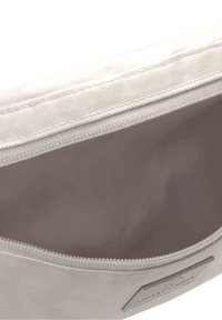 Béžová plátěná taštička s hladkým vnitřkem a zipovým uzávěrem, s texturovaným exteriérem a nášivkou na jedné straně.