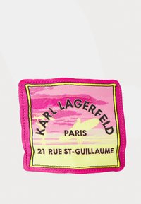 Wykonana z tkaniny naszywka w kolorze różowym, żółtym i czarnym, z napisem "Karl Lagerfeld Paris" i wzorem surferki, otoczona grubym różowym obramowaniem.