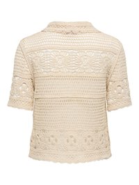 Blouse beige en crochet à manches courtes avec des motifs ajourés floraux et géométriques, dotée d’un col rond et de bords festonnés.