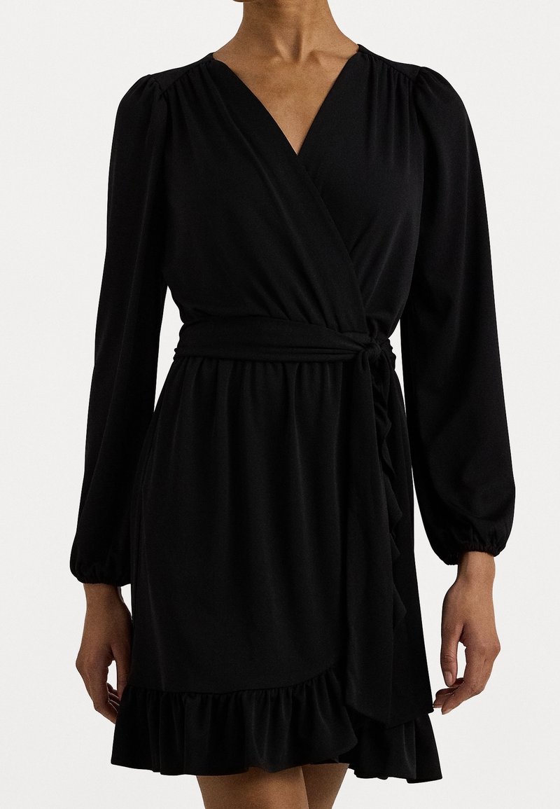 Svart omlottklänning med långa puffsleeves, markerad midja med bälte och en volangkant längst ner. Tillverkad av mjukt tyg med en slät textur.
