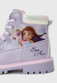 Des bottines à paillettes violettes présentent un accent holographique brillant sur le col, avec un graphisme de deux personnages et "Elsa Anna" en lettres cursives.