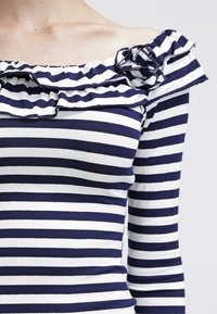 Gestreiftes Oberteil mit schulterfreien Trägern in Navy und Weiß, mit gerafftem Ausschnitt und kleinem Stoffblumenakzent.