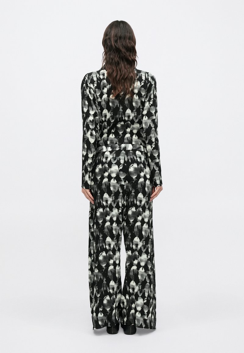 Sort-hvidt mønstret sæt med lange ærmer og bukser med vide ben. Glat stof med en løs pasform og abstrakte designdetaljer.