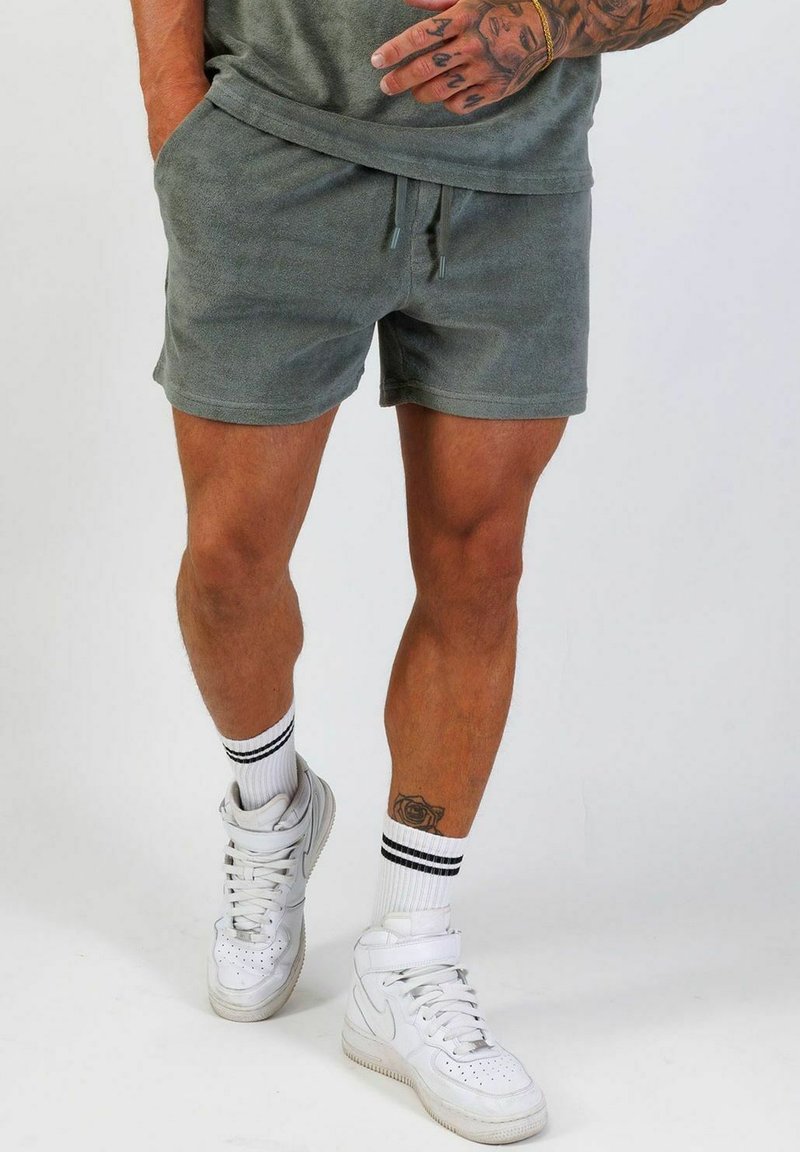 Gröna terraklottshorts med resårmidja och dragsko. Kombinerat med vita högskor och vitstrimmiga svarta strumpor.