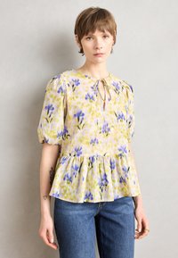 Blumenbluse in Gelb, Grün und Lila mit Puffärmeln, Peplum-Saum, Schlüssel-Ausschnitt und zartem Bindedetail.