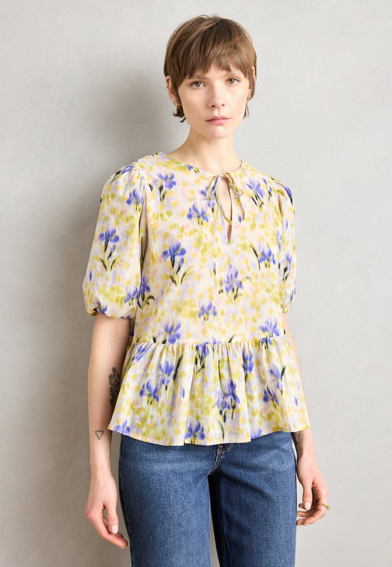 Blumenbluse in Gelb, Grün und Lila mit Puffärmeln, Peplum-Saum, Schlüssel-Ausschnitt und zartem Bindedetail.