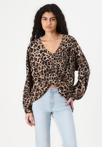 Leopardprintbluse med V-hals og lange, bløde ærmer. Fremstillet af letvægtsstof og har et knyttet frontdesign.