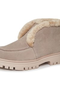 Botte cheville en suède tan avec une doublure en fausse fourrure beige moelleuse, bout rond et semelle en caoutchouc texturé dotée de rainures profondes pour une bonne adhérence.
