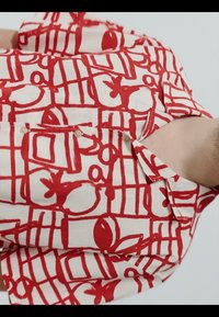 Chemise à col avec motifs abstraits de fruits rouges et quadrillage sur fond blanc, visible du cou au milieu du torse.