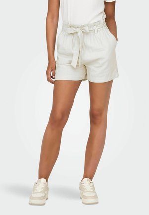 Lys beige linned shorts med elastisk talje, knyttet frontdetalje og sidelommer. Stylet med afslappede hvide sneakers.