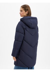 Manteau rembourré bleu marine avec un design en chevrons, capuche et manches longues. Fabriqué en matériau texturé et résistant à l'eau.