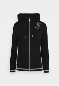 Svart zip-up hoodie med huva, silverdragkedja och dekorativa metalliska accentremsor vid ärmslut och nederkant. Har en logotyp tryckt på bröstet.