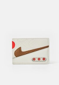 Portofel alb texturat cu un logo Nike swosh maro, accente roșii și trei orificii circulare pe o parte, având o finisare din piele netedă.