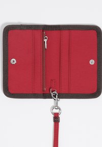Interno di un portafoglio in tessuto rosso con rifiniture beige, dotato di più slot per carte, una tasca con zip, chiusure a scatto e una tracolla staccabile con accessori.