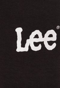 Svart tyg med en stor, vit, texturerad logotyp som läser "Lee" med ett registrerat varumärkessymbol i hörnet.