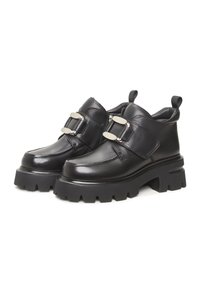 Bottines en cuir noir avec une semelle à crans épaisse, des boucles latérales et des languettes à l'arrière. Texture lisse avec un design épuré et des accents minimalistes.