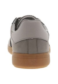 Baskets en suède gris avec une accent en cuir lisse, forme arrondie et semelle en caoutchouc gum. La vue arrière montre des détails cousus et un col rembourré.