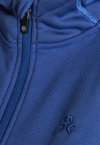 Modra zip-up kapuca narejena iz gladkega blaga. Ima izvezen logo na levi strani in kontrastne šive ob šivih.