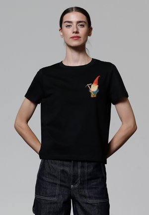 T-shirt en coton noir avec un design de gnome coloré brodé sur la poitrine gauche, manches courtes et col rond.