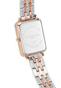 Reloj rectangular con una correa de acero inoxidable en plata y oro rosa. Presenta una parte trasera pulida con texto grabado. Movimiento japonés. Resistencia al agua de 34 mm.