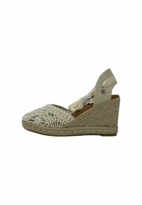 Sandalia de cuña con suela de yute trenzado, parte superior de ganchillo blanca y interior marrón. La correa ajustable presenta un patrón a cuadros y un herraje decorativo.