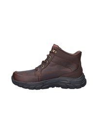 Bruine leren enkelboot met een gestructureerd oppervlak, metalen oogjes en een gevoerde zwarte rubberen zool voor grip en ondersteuning.