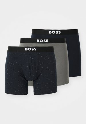 Tre par herrebokserbukser: marineblå med prikker, ensfarvet marineblå og grå. Alle har sorte taljer med "BOSS" logo i hvid. Blandingsmateriale af bomuld.