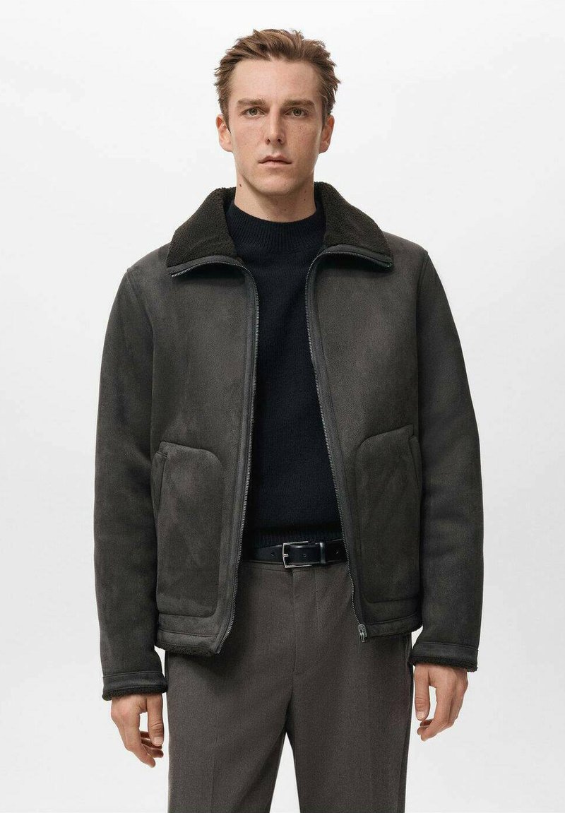 Giacca in suede grigio scuro con zip frontale, colletto morbido e due grandi tasche anteriori. Texture morbida e vestibilità rilassata.