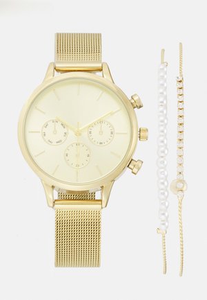 Goldfarbener Metall-Mesh-Armbanduhr mit cremefarbenem Ziffernblatt, drei Subdials und goldenen Akzenten. Enthält zwei Armbänder: eines mit Perlen und ein weiteres mit Kristallen.